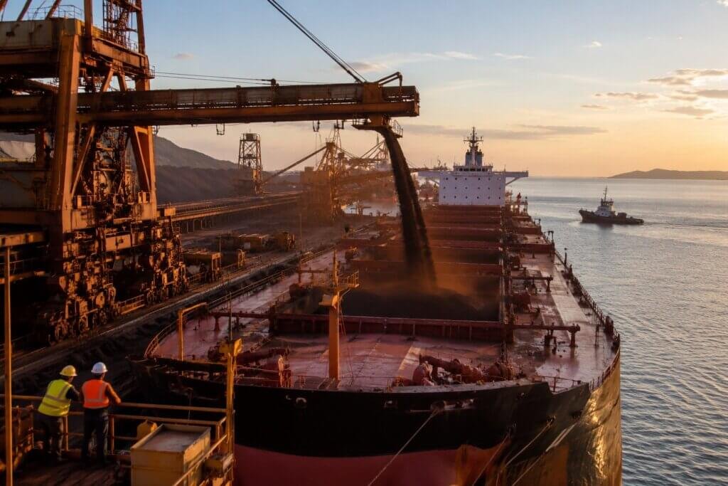 Terminal portuário brasileiro com embarque de minério de ferro em navios cargueiros em cenário econômico industrial realista.